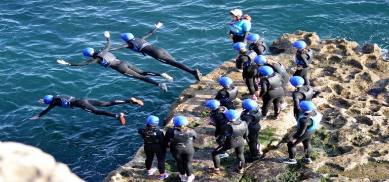 school group diving off rocks into the sea