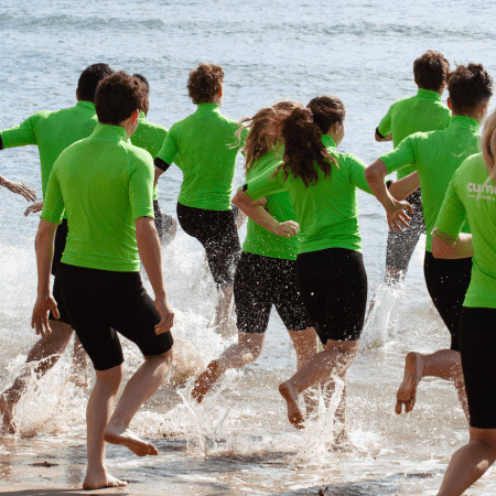 school group running into the sea at the coast in Swanage