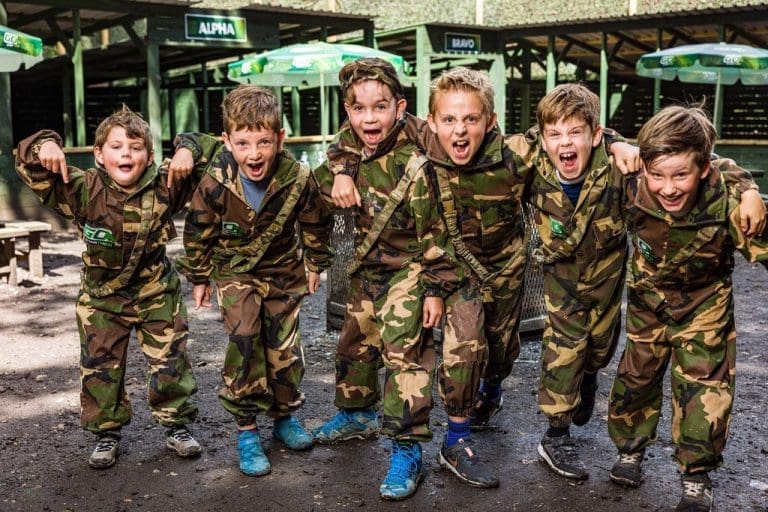 primary school pupils dressed in combat gear doing paint balling