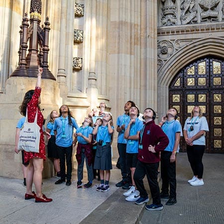 school pupils looking up at the houses of parliament building on a school trip