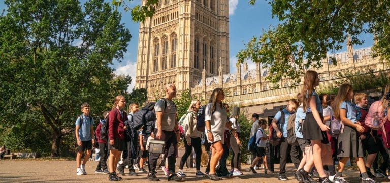 school pupils in a group at the houses of parliament on a school trip