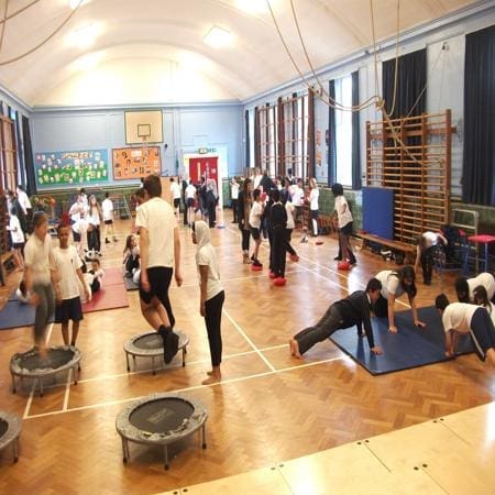 school pupils working in the gym at school doing physical exercises