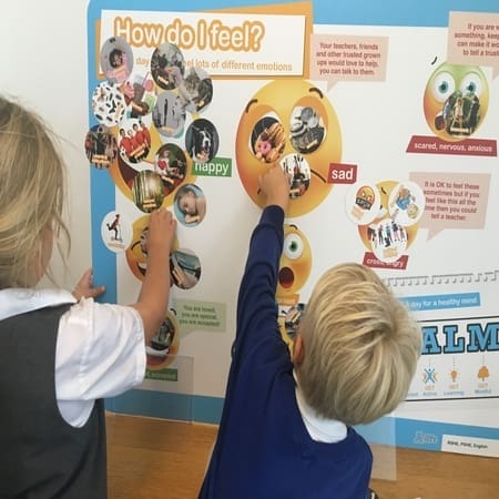 primary school children working off a how do you feel poster board at school