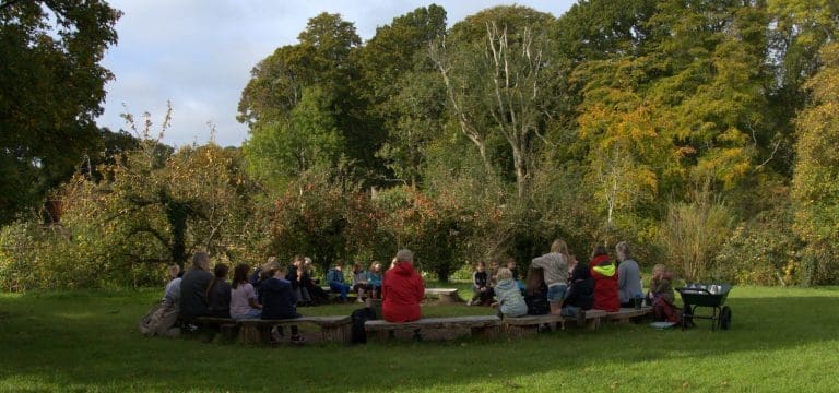 school trip group around a storey telling circle in a field at minstead study centre