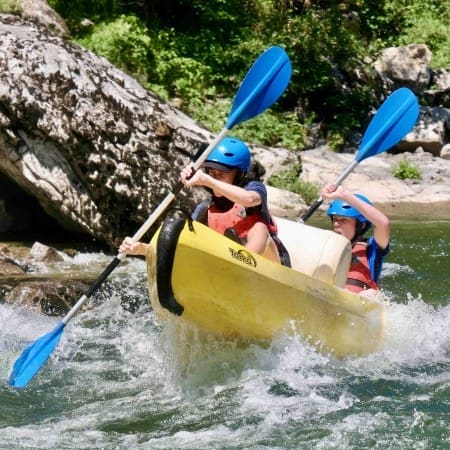 two students in a kayak going down a river