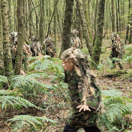 school children in the woods play laser tag