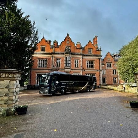a coach parked next to a Georgian historic building in the car park