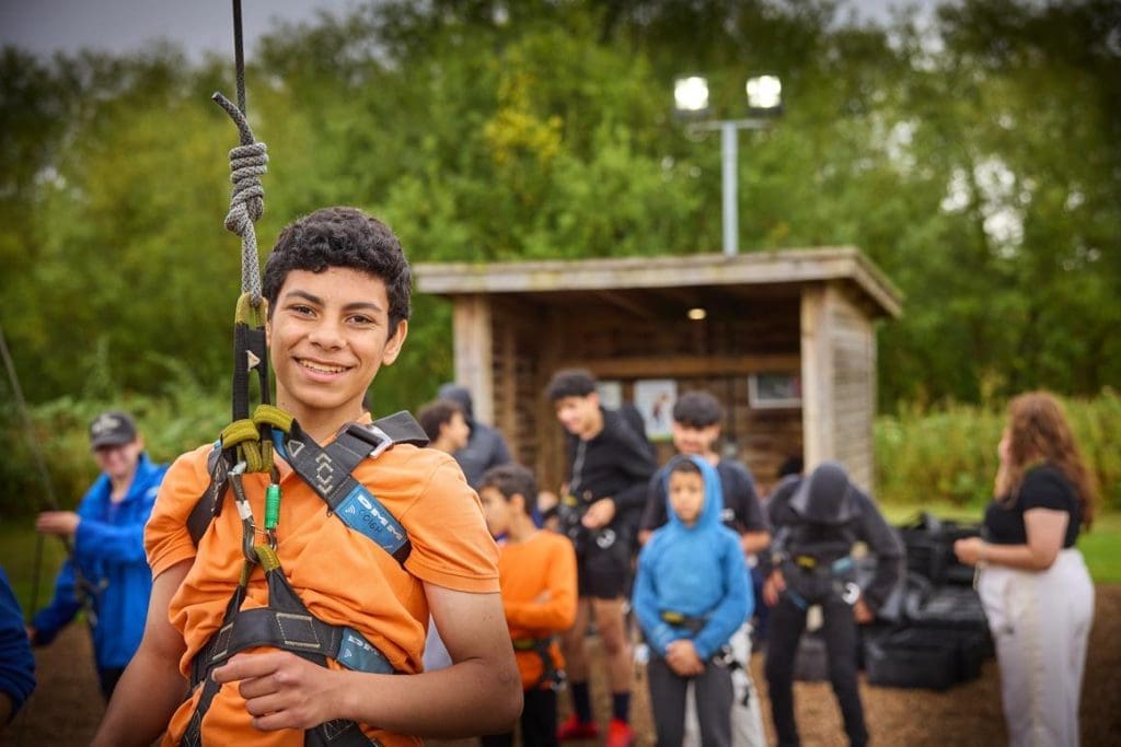 group of school pupils putting safety gear on for adventure activities