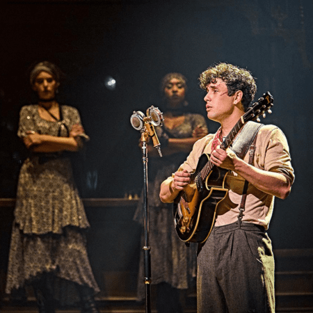 tree actors on stage one playing a guitar lyric theatre London