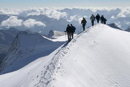 school pupils hiking on top of a mountain range in the snow