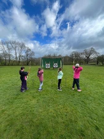 pupils doing archery on a range in a field