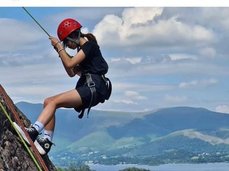 school pupil abseiling down a rock face